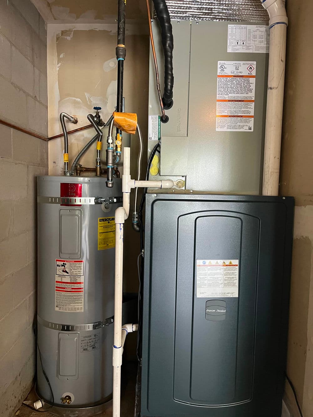 Gas furnace and water heater installed in a home utility room with safety labels visible.