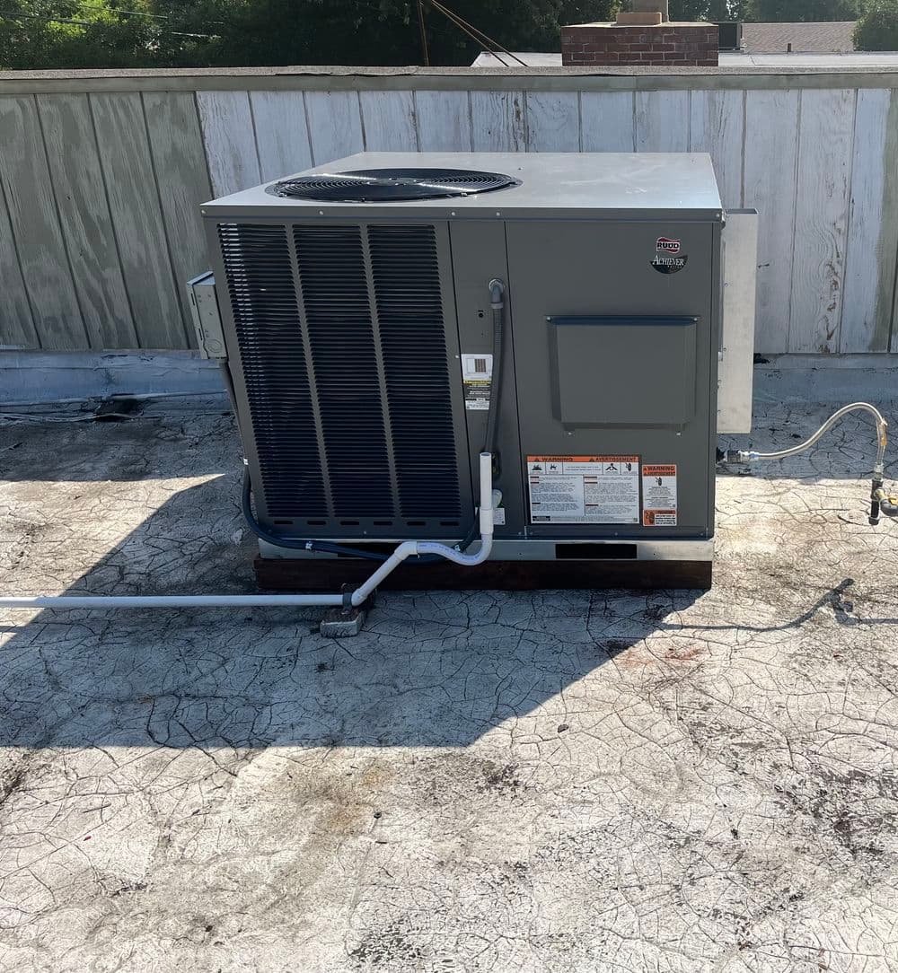 Rooftop air conditioning unit with visible plumbing and electrical connections.